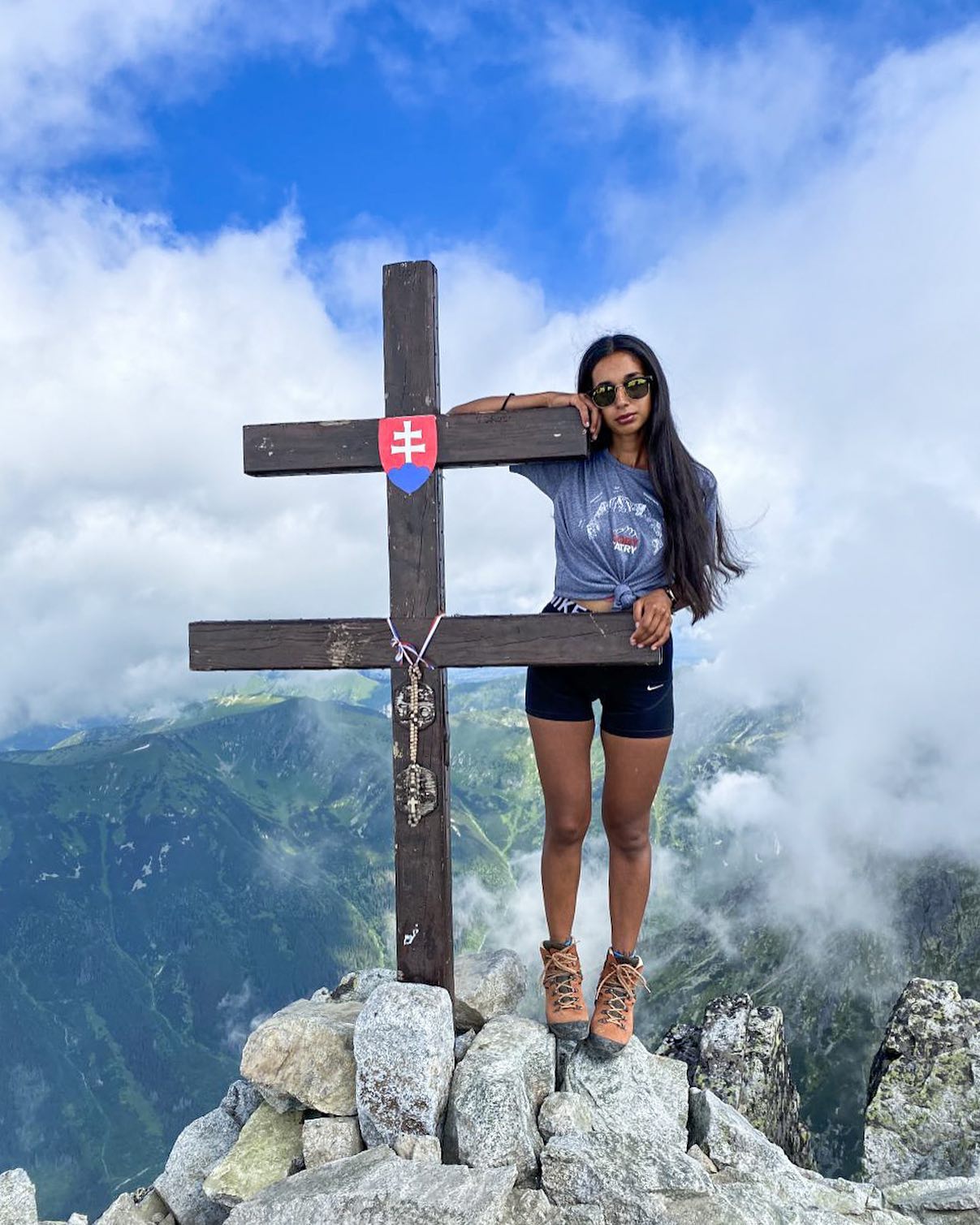 Un participante junto a la cruz de una cumbre, sobre las nubes