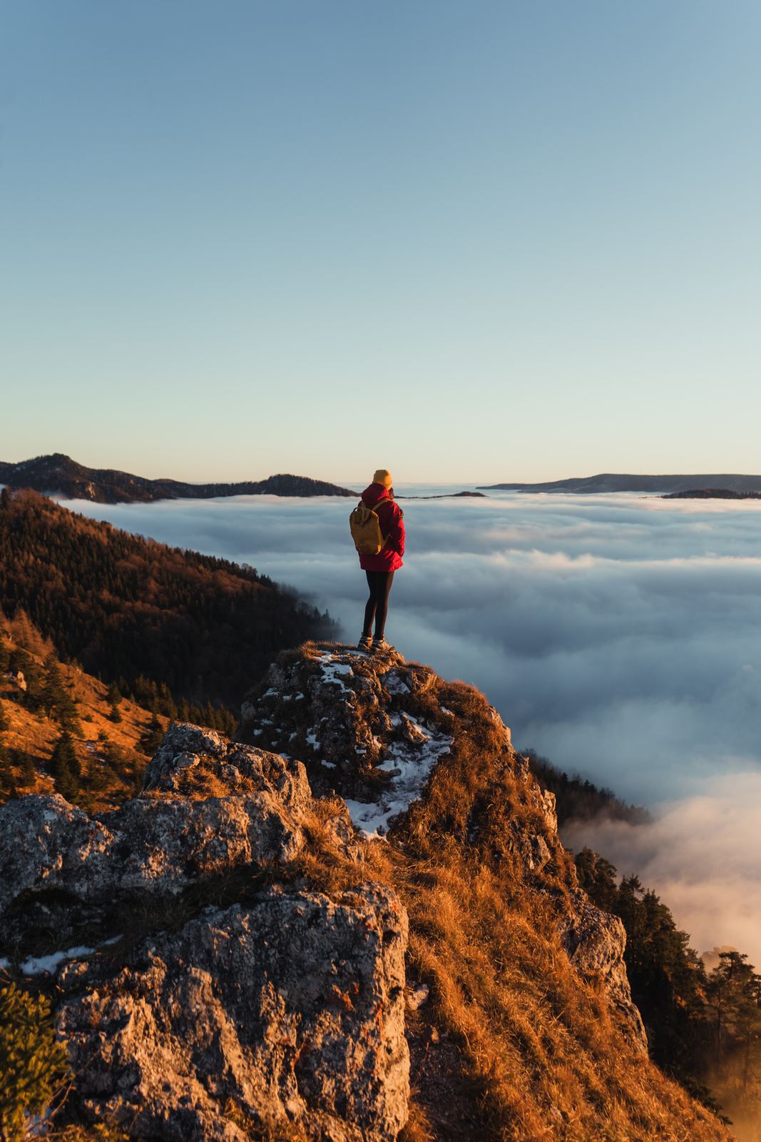 Un senderista sobre una roca, encima de un mar de nubes